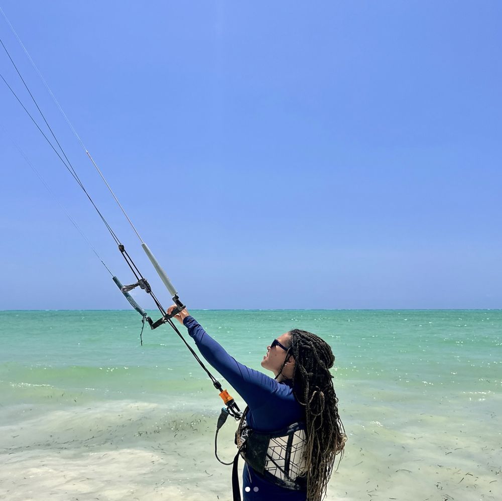 A student holding the control bar and looking up at the kite on the Paje shore